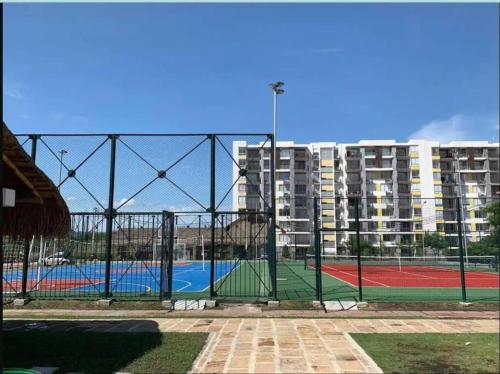 a tennis court behind a fence with buildings in the background at Brisas la aldea in Ricaurte