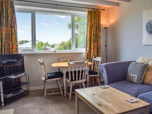 a living room with a blue couch and a table and a window at Top Croft in Beadnell