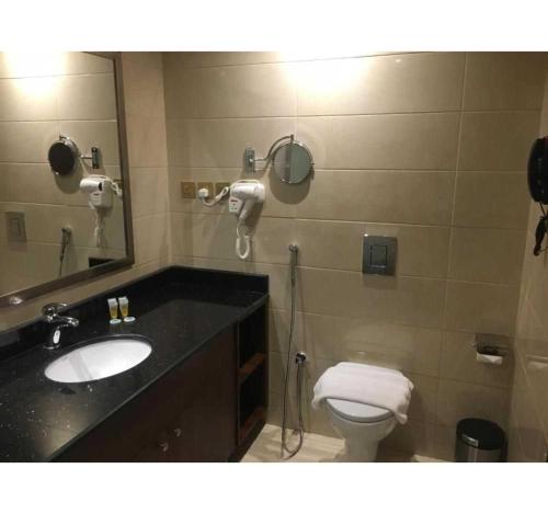 a bathroom with a sink and a toilet and a mirror at Dancenter Red Sea Fountain Alhamra Vivid Plaza Hotel in Jeddah