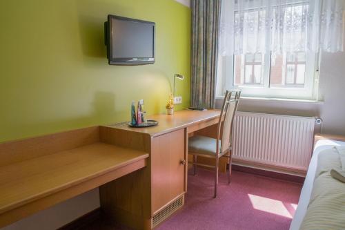 a hotel room with a desk and a tv on the wall at Hotel zur Post in Wurzen in Wurzen