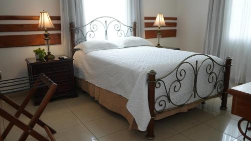 a bedroom with a bed and a window and a chair at Hotel Casa del Arbol in San Pedro Sula