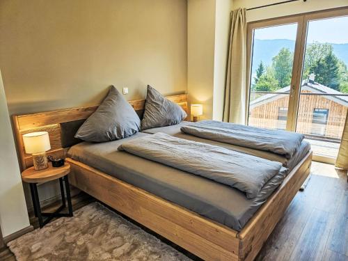 a bedroom with a bed with a large window at Chalet Ossiacher See Chalet 2 by Interhome in Bodensdorf
