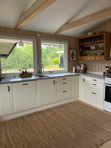 a kitchen with white cabinets and a large window at Holiday Home Close To The Beach In Nødebohuse in Hundested