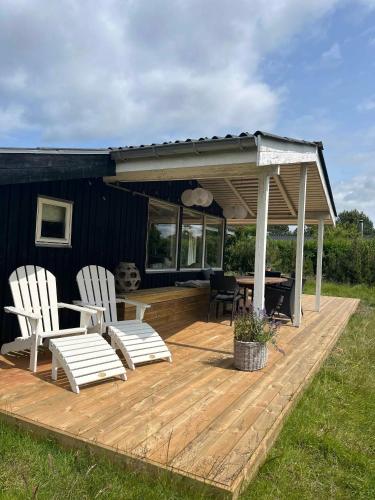 a wooden deck with two chairs and a table at Holiday Home Close To The Beach In Nødebohuse in Hundested