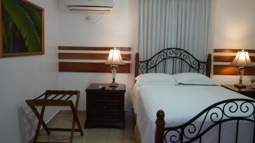a bedroom with a bed and a chair and two lamps at Hotel Casa del Arbol in San Pedro Sula