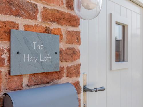 a sign on a brick wall next to a door at The Hayloft - Uk34565 in Whitchurch