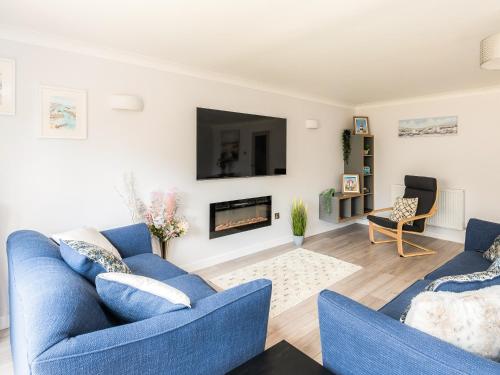 a living room with two blue couches and a fireplace at Seascape in Sheringham