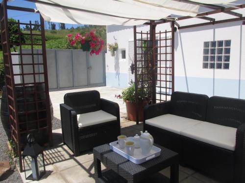 a patio with a couch and chairs and a table at Casa Formiga in Fajã da Ovelha