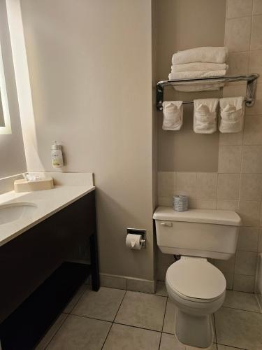 a bathroom with a toilet and a sink and towels at Super 8 by Wyndham Thunder Bay in Thunder Bay