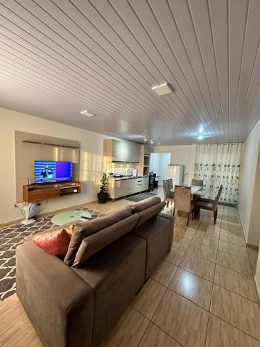 a living room with a large couch and a kitchen at Morada Felicitá in Pato Branco