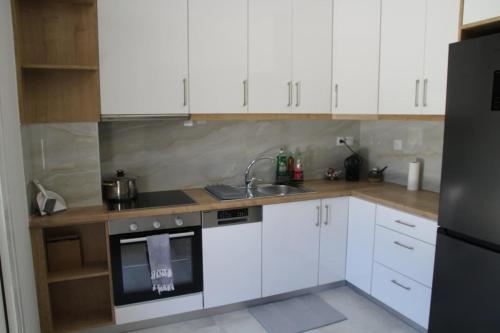 a kitchen with white cabinets and a sink at Thaleia apartment in Ladochórion