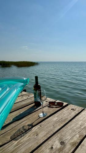 a bottle of wine and a glass sitting on a dock at Retro Lakefront House With A Dock in Balatonvilágos