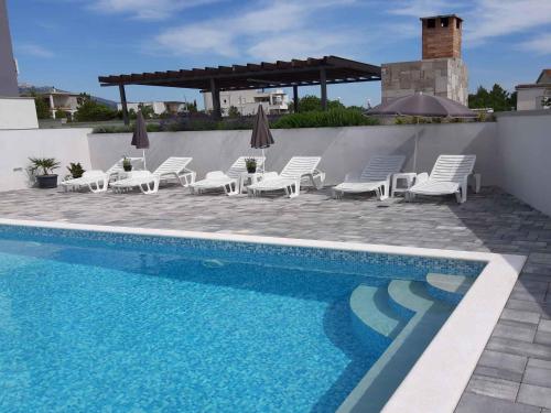 une piscine avec des chaises longues et une piscine dans l'établissement Apartments in Starigrad-Paklenica 41220, à Starigrad-Paklenica
