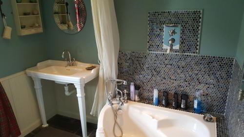 a bathroom with a bath tub and a sink at Quaraing House in Staffin
