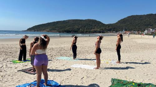 a group of people standing on a beach at Nômades Beach - Adventure Hostels in Florianópolis