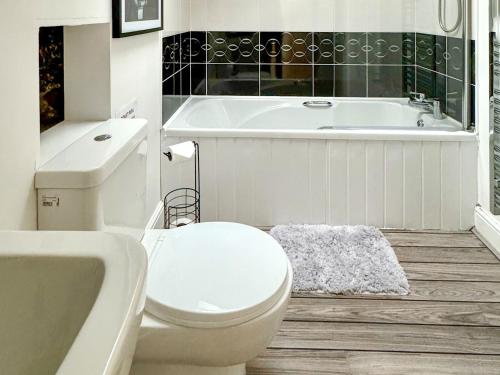 a white bathroom with a tub and a toilet and a sink at Oak Tree Barn - 27693 in Otterburn