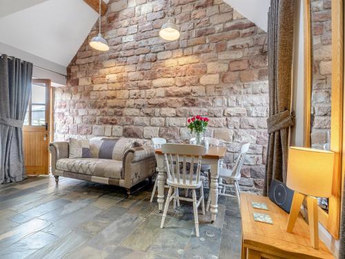 sala de estar con pared de ladrillo, mesa y sillas en Jacob's Barn - Uk46733, en Wootton