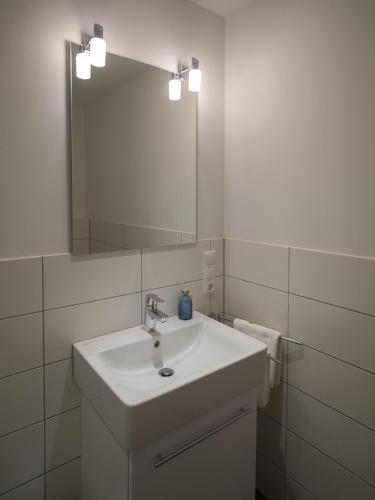 a white bathroom with a sink and a mirror at Hotel Inselfriede in Spiekeroog