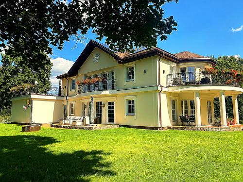 a large yellow house with a lawn in front of it at Gulbės Apartamentai in Anykščiai