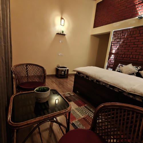 a room with a bed and a table and chairs at Meru Stays in Mukteswar