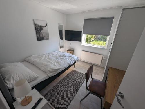 a small bedroom with a bed and a chair at Suburban house in Rødbyhavn in Rødby