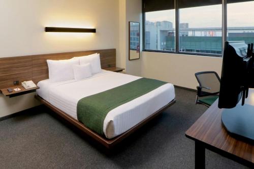 a hotel room with a bed and a desk and window at City Express Plus by Marriott Ciudad de México Santa Fe in Mexico City