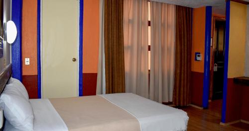 a bedroom with a white bed and colorful walls at Hotel Benedicta in Mexico City