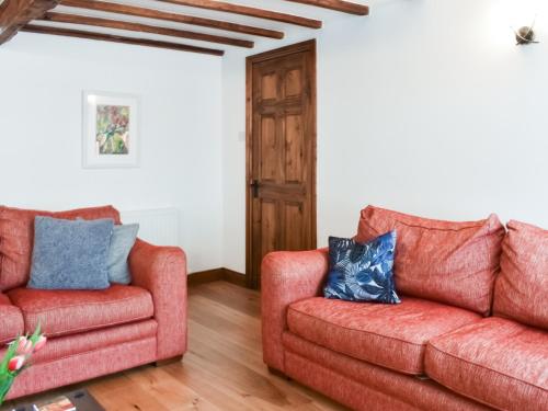 two red couches sitting in a living room at Summerville Cottage in Kirkby Stephen