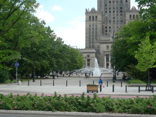 a woman walking in front of a fountain in a park at Center Apartment in Warsaw