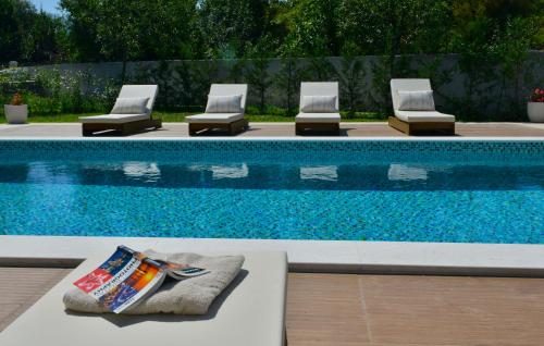 a swimming pool with four lounge chairs next to it at Villa Jovanovic in Tivat