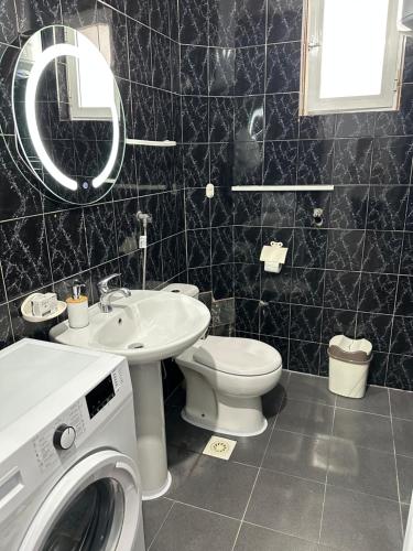 a bathroom with a toilet sink and a washing machine at Apartment Center Korça in Korçë