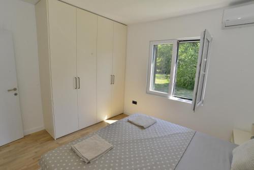 a white bedroom with a bed and a window at Villa Jovanovic in Tivat