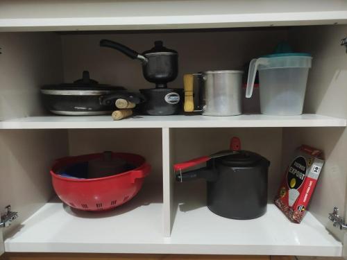 a shelf with pots and pans and other kitchen items at Apartamento bem localizado para até 4 hóspedes in Brasilia