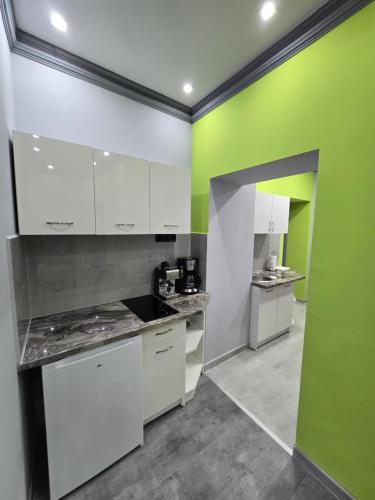 a kitchen with white cabinets and a green wall at White House Apartman Miskolc, Green Room in Miskolc