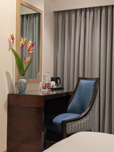 a bedroom with a desk with a chair and a mirror at Meritas Grand Inn Calangute in Calangute