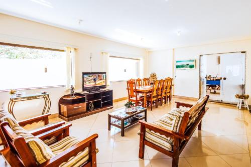 a living room with chairs and a television and a table at VELINN Pousada Mirante da Praia Grande in Ilhabela