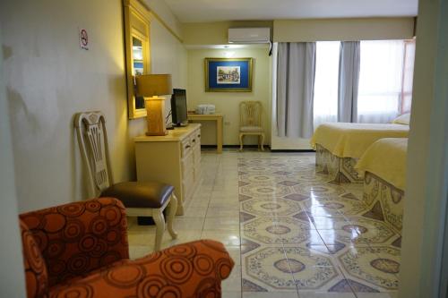a hotel room with a bedroom with a bed and a chair at Hotel Posada del Sol Inn in Torreón