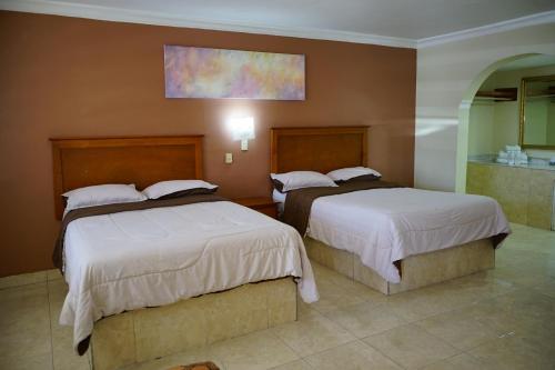a hotel room with two beds and a bathroom at Hotel Posada del Sol Inn in Torreón
