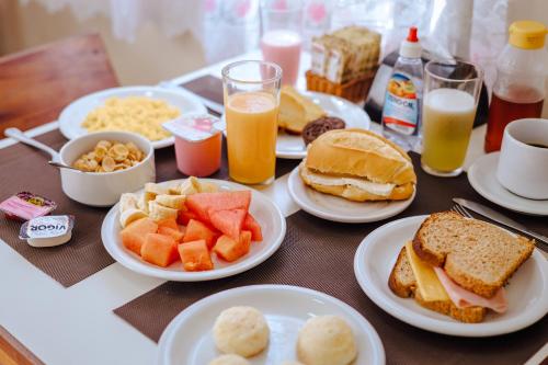 a table with plates of breakfast foods and drinks at VELINN Pousada Mirante da Praia Grande in Ilhabela