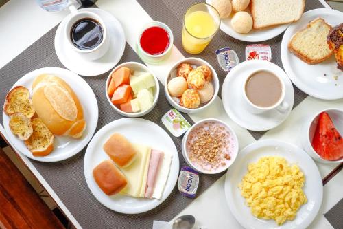 a table with plates of breakfast foods and cups of coffee at VELINN Pousada Mirante da Praia Grande in Ilhabela