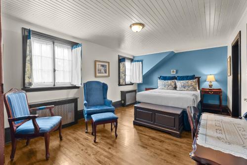 a bedroom with blue walls and a bed and chairs at Le Clos Saint-Louis in Quebec City