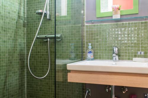 baño de azulejos verdes con ducha y lavamanos en Appartement Le Buffon en Dijon