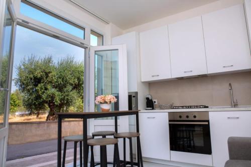 a kitchen with white cabinets and a table with stools at Perla D'Itria in Locorotondo