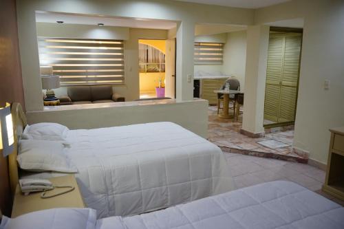 a bedroom with two beds and a living room at Hotel Posada del Sol Inn in Torreón