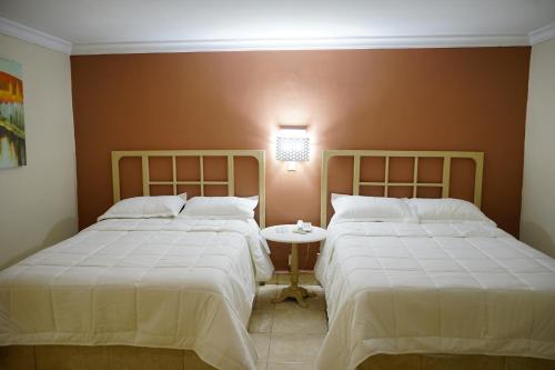 a bedroom with two beds and a table between them at Hotel Posada del Sol Inn in Torreón