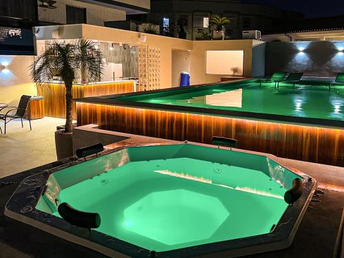 a swimming pool with a large green tub in a building at Pousada Valle Verde in Cabo Frio