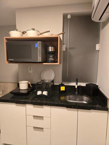 a kitchen with a sink and a microwave at Studio Triplo M3 Hotel in Camaçari
