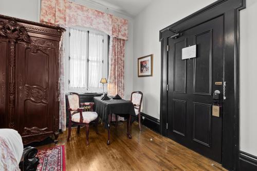 a bedroom with a table and chairs and a black door at Le Clos Saint-Louis in Quebec City