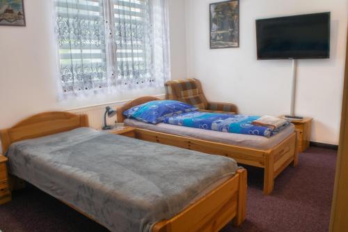 a room with two twin beds and a tv at Penzion K in Rudník
