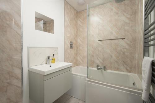 a white bathroom with a sink and a shower at Northumberland Hot Tub Haven for 10 in 5 ensuite bedrooms in Chatton